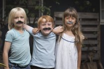 Children in fake mustaches smiling at camera — Stock Photo
