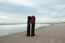 Kariertes Hemd auf Holzplanken am Sandstrand bei bewölktem Tag — Stockfoto