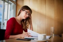 Geschäftsfrau liest Papierkram am Vorstandstisch — Stockfoto