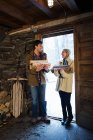 Couple holding logs and smiling at each other in rustic house — Stock Photo