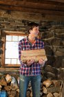 Portrait of man holding logs in rustic house — Stock Photo