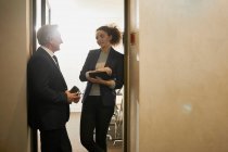 Бізнесмен і жінка розмовляють в офісних дверях — стокове фото