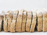 Whole grain oat bread slices on white surface — Stock Photo