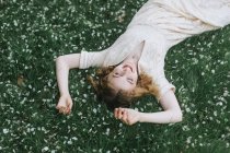 Mulher deitada em flor coberto grama — Fotografia de Stock