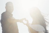 Portrait of couple outdoors, hands touching, making heart shape — Stock Photo