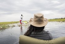 Visão traseira da mulher jovem em canoa no Okavango Delta, Botsuana, África — Fotografia de Stock