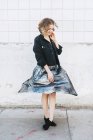 Женщина на улице крутит металлическую юбку к стене — стоковое фото
