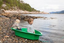 Niños en barco verde en el borde del fiordo, Aure, Más og Romsdal, Noruega - foto de stock