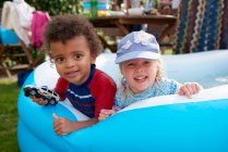Two toddlers playing in paddling pool, portrait — Stock Photo