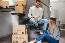 Couple sitting with cardboard boxes, moving home — Stock Photo