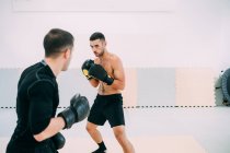 Homme avec entraîneur personnel sparring en salle de gym — Photo de stock