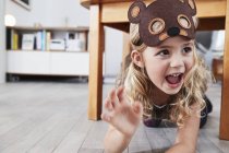 Young girl crawling under table in bear mask — Stock Photo