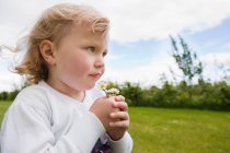 Girl holding daisies and looking away — Stock Photo