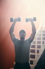 Homme utilisant des haltères dans la salle de gym — Photo de stock
