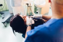 Dentista que realiza procedimiento dental en paciente femenino - foto de stock