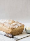 Loaf of fresh bread with butter and knife, close-up view — Stock Photo