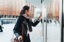 Frau benutzt Smartphone und trägt Gepäck — Stockfoto