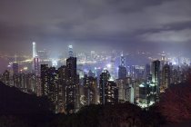 Paisaje urbano de rascacielos iluminado por la noche, Hong Kong, China, Asia Oriental - foto de stock