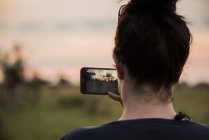 Вид сзади на молодую женщину, фотографирующуюся со смартфоном в дельте Окаванго, Ботсвана, Африка — стоковое фото