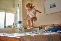 Femme tout-petit sautant en plein air sur le lit — Photo de stock