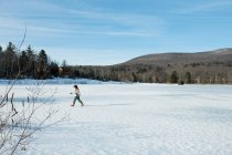 Fille marche sur la neige avec des patins à glace — Photo de stock