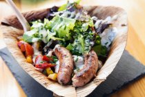 Sausages and salad in palm leaf plate — Stock Photo