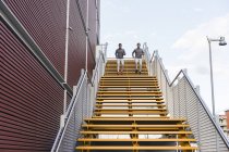 Gemelos varones jóvenes corriendo por las escaleras de la ciudad - foto de stock