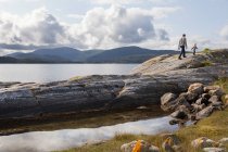 Man and son walking on fjord rock formation, Aure, More og Romsdal, Norvège — Photo de stock