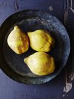 Still life of three quinces in metal pan, overhead view — Stock Photo