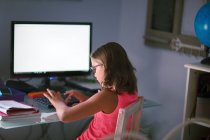 Молода дівчина робить домашнє завдання і використовує комп'ютер — стокове фото