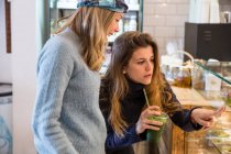 Junge Frau und Freund betrachten Vitrine mit frischen Lebensmitteln im Café — Stockfoto
