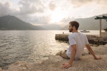 Joven sentado junto al agua en Kotor, Montenegro, Europa - foto de stock