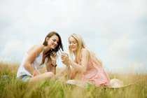 Junge Frauen schauen auf dem Feld auf das Smartphone — Stockfoto