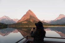 Mujer tomando fotos cerca de Swiftcurrent Lake, Glacier National Park, Montana, Estados Unidos - foto de stock