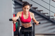 Woman in gym using exercise bike — Stock Photo