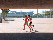 Junges Paar läuft tagsüber in Sportbekleidung im Freien — Stockfoto