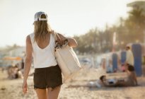 Вид сзади на женщину, идущую вдоль пляжа — стоковое фото