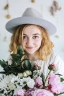 Portrait of smiling woman holding bunch of flowers, looking at camera — Stock Photo