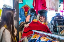Friends browsing vintage clothes in thrift store — Stock Photo