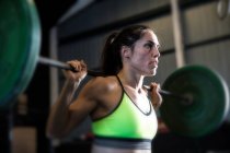 Woman exercising in gym, using barbell — Stock Photo
