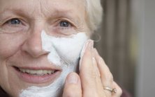 Close up de mulher sênior aplicando máscara facial — Fotografia de Stock