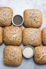 Vue aérienne des petits pains multgrain avec un bol de graines — Photo de stock