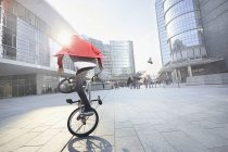 Jeune homme faisant cascade avec BMX vélo en zone urbaine — Photo de stock