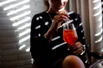 Обрезанный снимок счастливой молодой женщины, пьющей коктейль Spritz в бутик-ресторане отеля, Италия — стоковое фото
