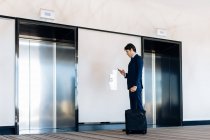 Businessman with wheeled luggage by hotel lift — Stock Photo