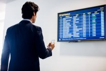 Businessman checking departure board — Stock Photo