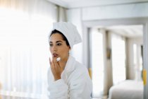 Mujer aplicando bálsamo labial en suite - foto de stock