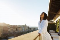Mujer disfrutando del sol en el balcón del hotel, Florencia, Toscana, Italia - foto de stock