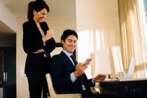 Бізнесмен і бізнес-леді, що ділиться текстовим повідомленням в готельному номері — стокове фото