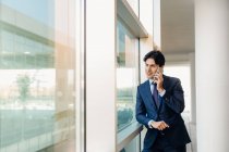 Geschäftsmann benutzt Handy am Fenster — Stockfoto